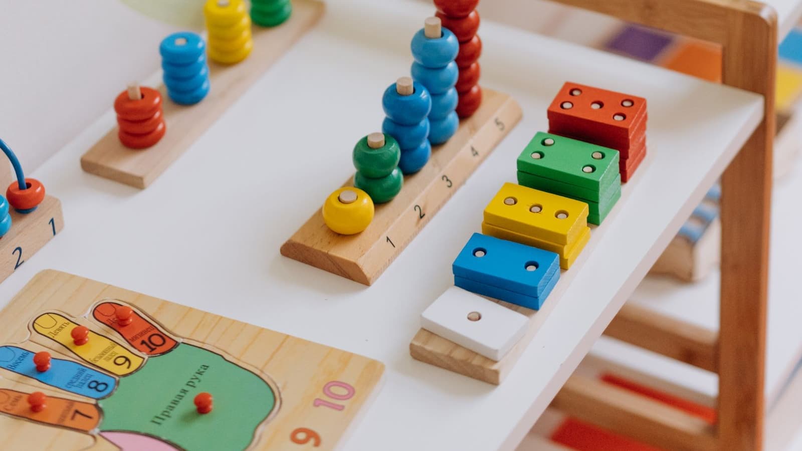 Colourful wooden counting and stacking toys arranged on a low shelf