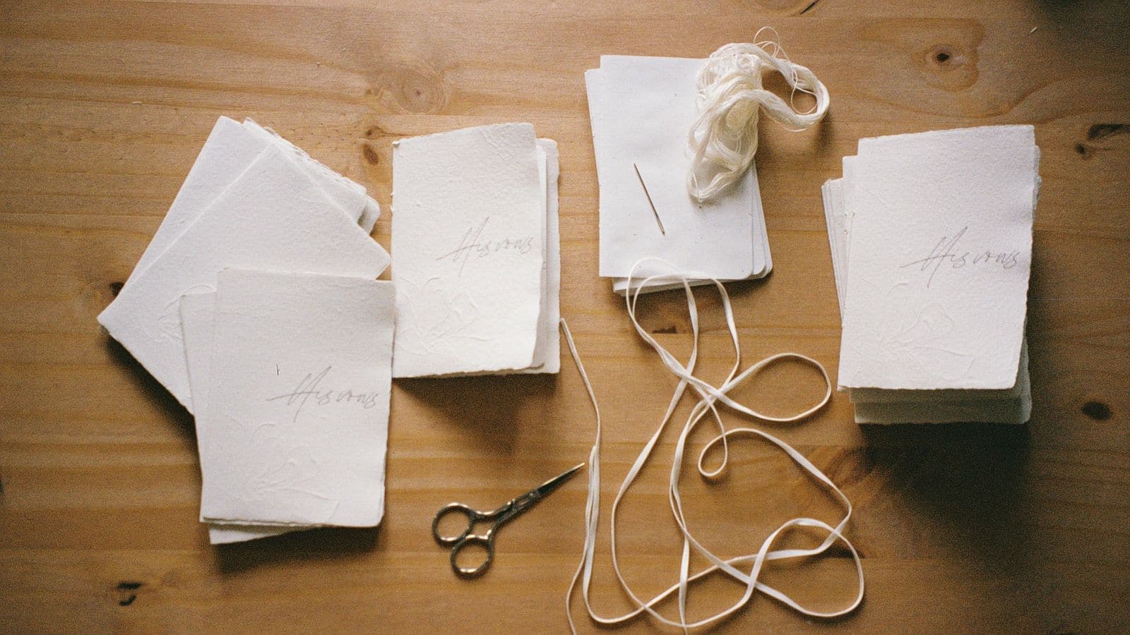 Handmade paper, scissors and thread laid out on a wooden table